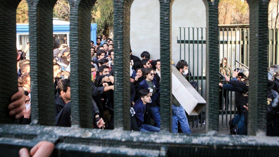 Iranian students clash with riot police during an anti-government protest around the University of Tehran. One man hold a concrete block in front of police carrying batons and shields.