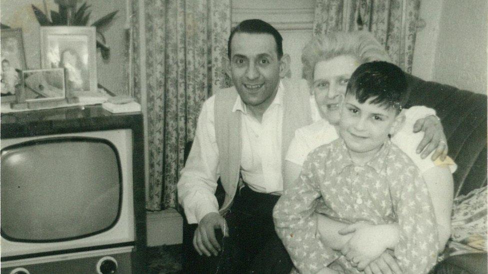 Black and white photograph of Howard Bernstein as a child with his mother and father at home