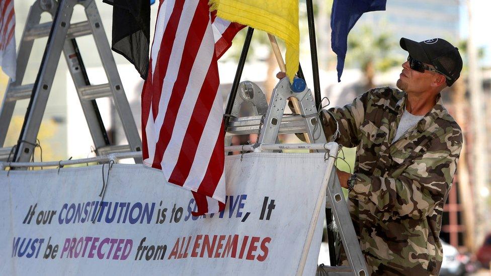 A supporter of Nevada rancher Cliven Bundy and his family, attaches a flag to a sign outside the federal courthouse in Las Vegas