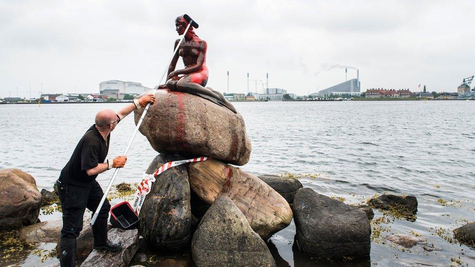 A man cleans the red paint off the Little Mermaid in 2017