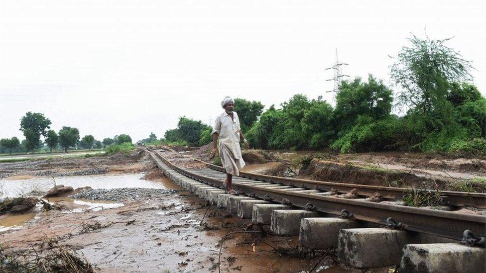 In this photograph taken July 29, 2017 an Indian villager walks along damaged railway tracks due to floods at Godha village of Deesa taluka, some 195km from Ahmedabad.