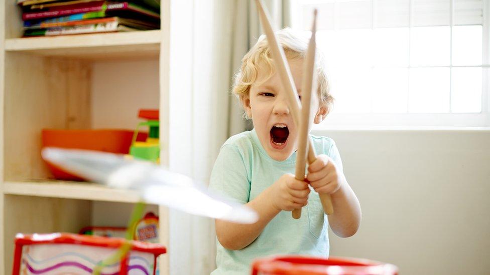 A little boy playing with a toy drum