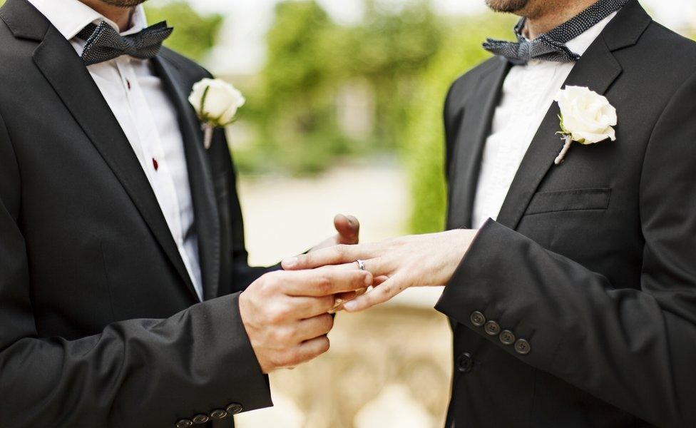 A gay couple exchange rings at their wedding