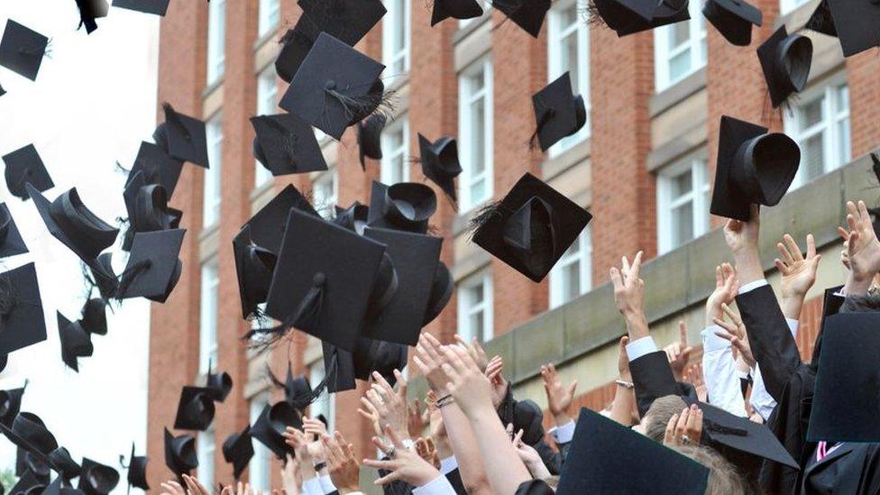 Graduating students throw their square caps in the air