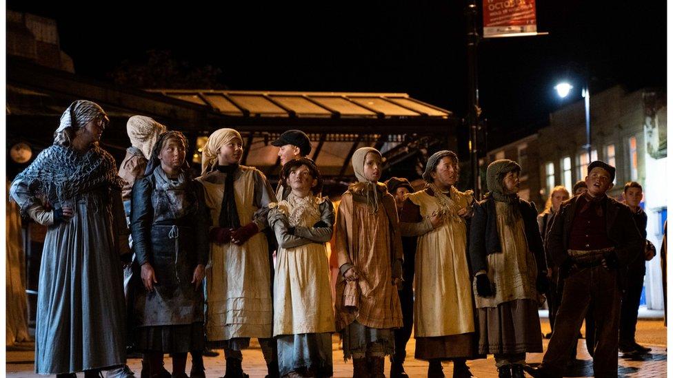 A scene from a Theatr Clwyd street production depicting the 1869 Mold Riots - a row of children in dirty 19th century-style clothes