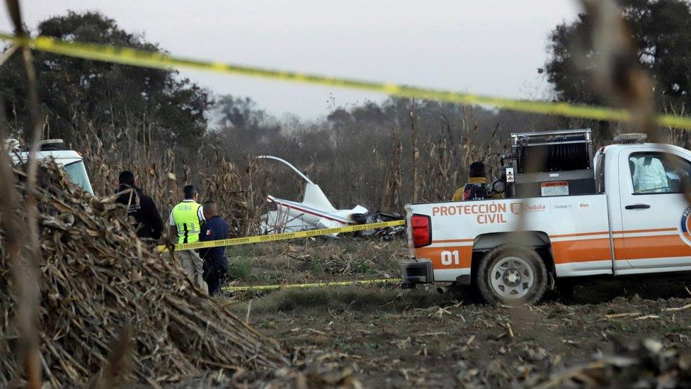 Police and rescue personnel stand at the scene of the crash