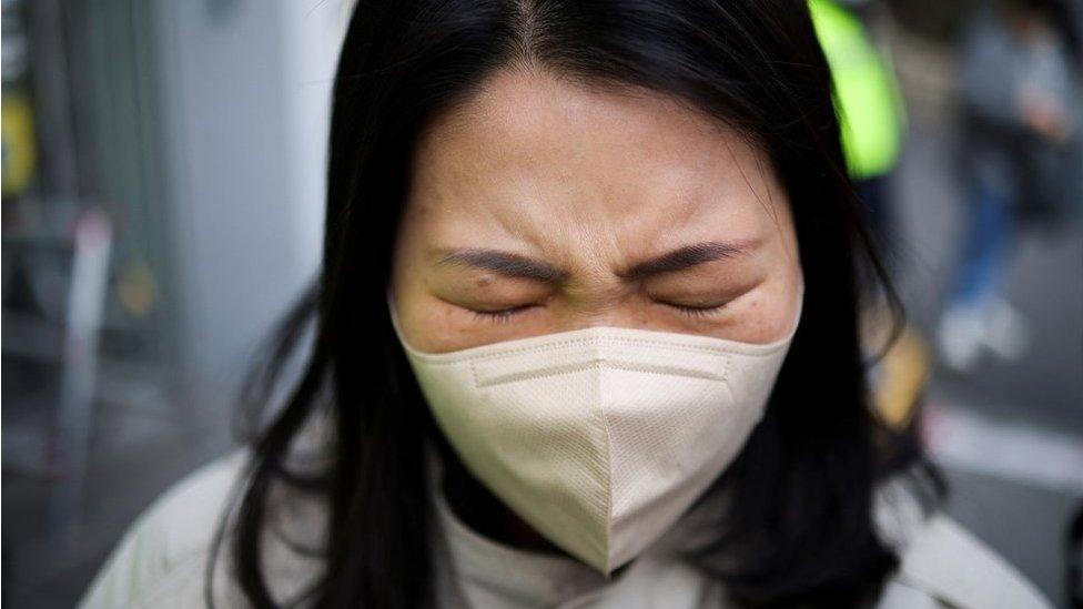 A woman mourns at a floral tribute near the scene of a crowd crush that happened during Halloween festivities, in Seoul, South Korea, November 1, 2022