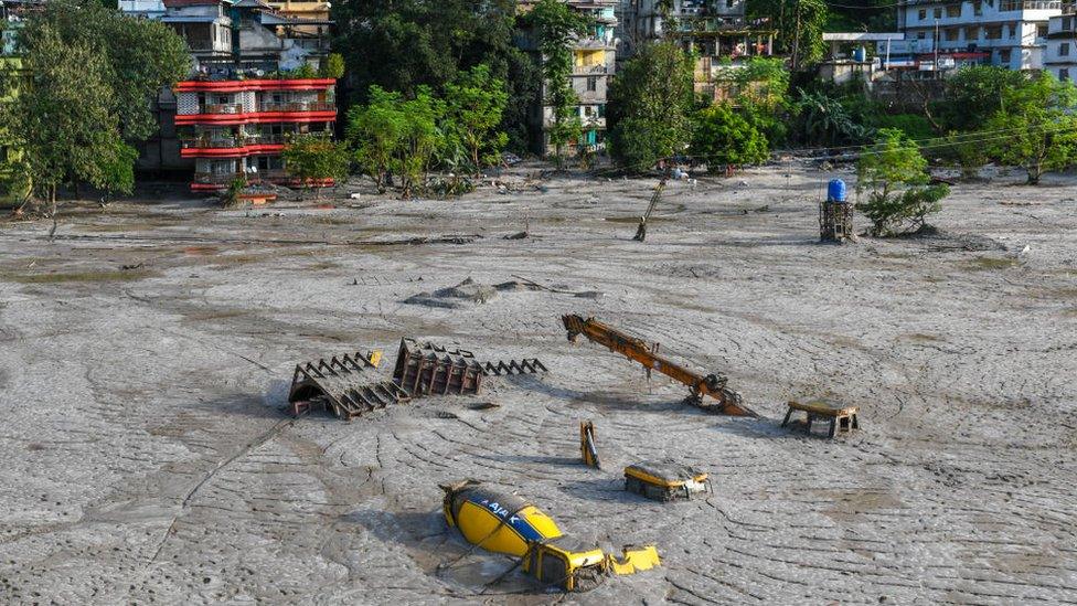 RANGPO, SIKKIM, INDIA - 2023/10/09: Construction vehicles are seen covered in debris caused by flash floods after a lake burst in Rangpo along the Teesta River. After a glacial lake in northeast India burst through a dam shortly after midnight, washing away homes and bridges and forcing thousands to flee, rescue workers continued to dig through muddy debris. (Photo by Biplov Bhuyan/SOPA Images/LightRocket via Getty Images)