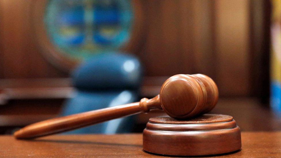 A gavel and a block is pictured on a judge's bench