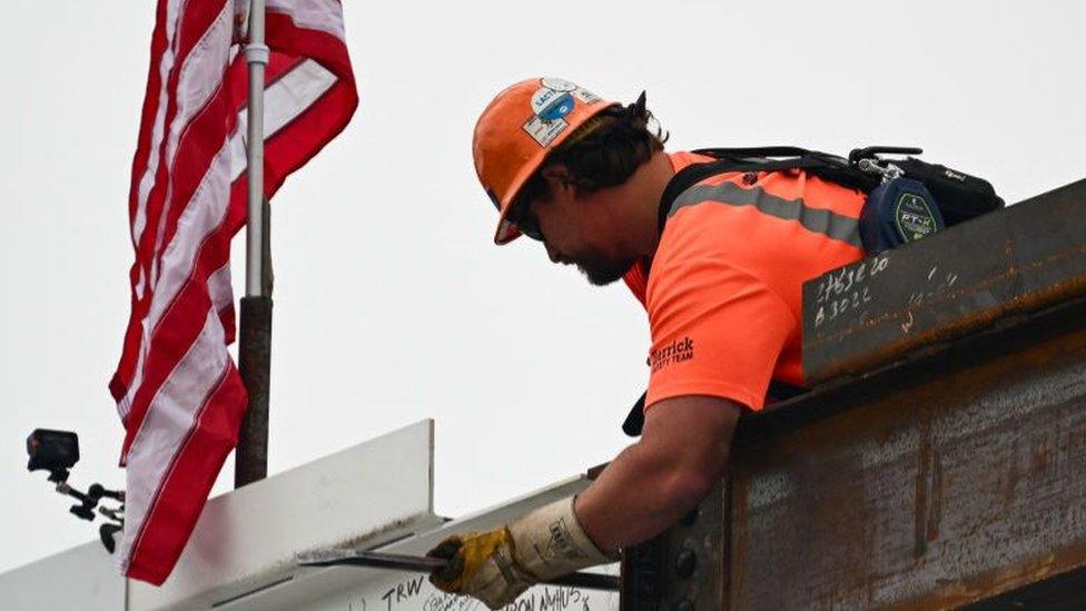 A construction worker with the American flag in the background