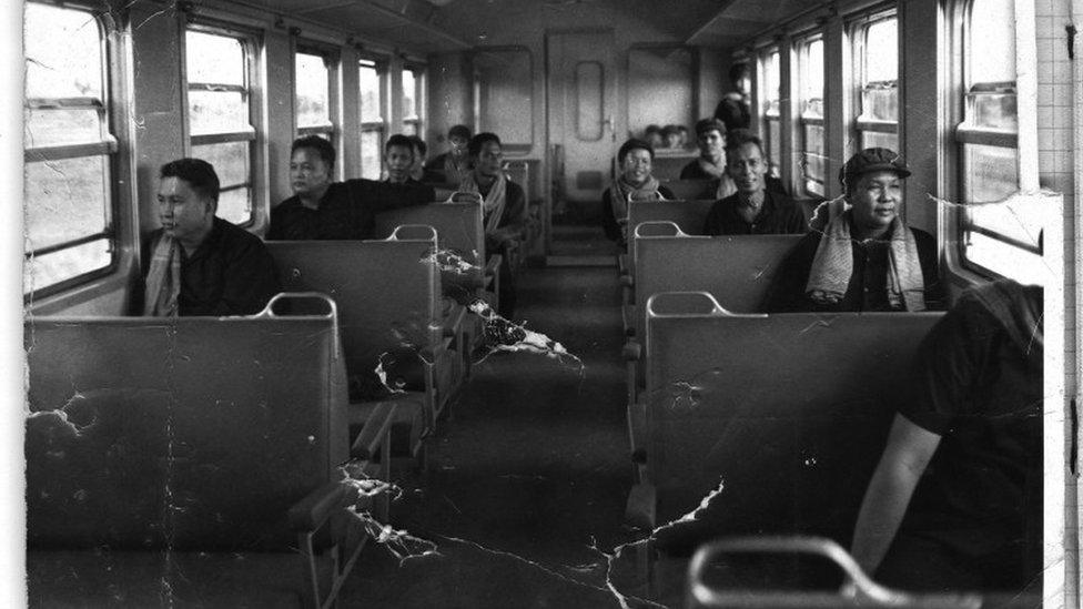 Pol Pot, front left, sits on a train in 1975, with Nuon Chea directly behind