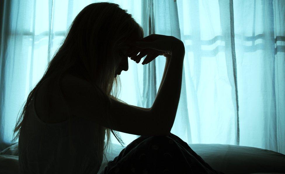 Silhouette of woman in front of curtain