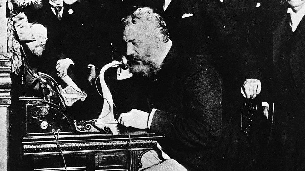 alexander graham bell talking through an early version of the telephone