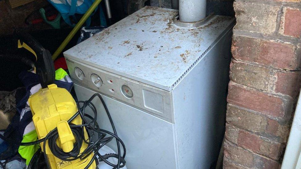 Floor-standing boiler in an brick outhouse with dirt on the surface