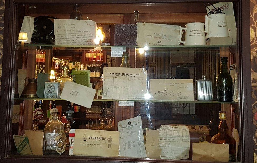 A cabinet in the pub containing old bottles and documents