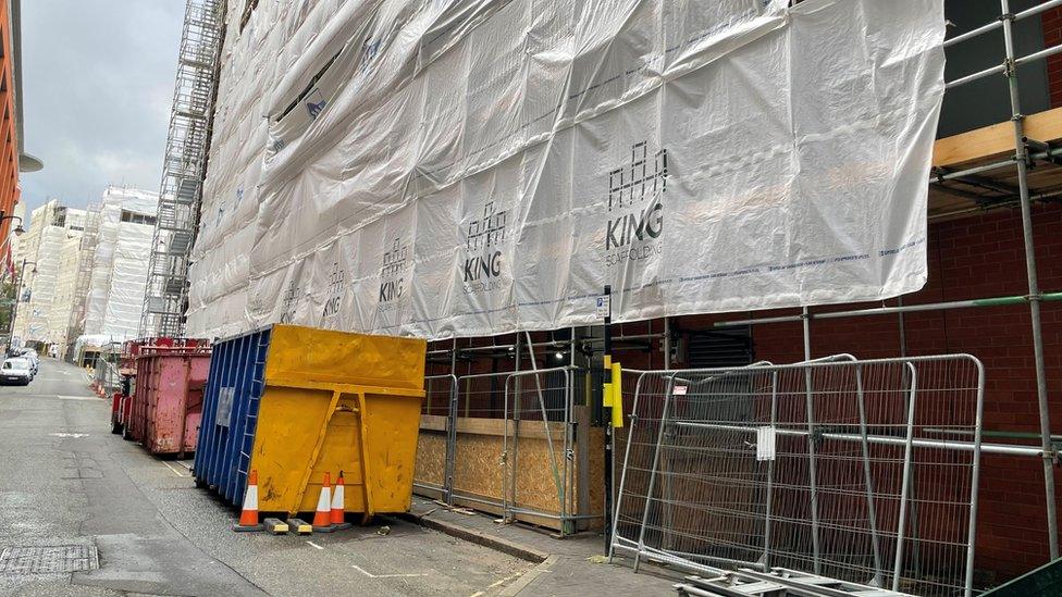 Exterior of Islington Gates showing parking bays closed off with skips and metal barriers