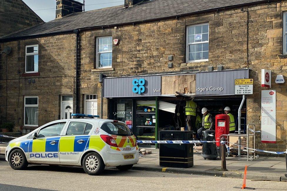 A police car outside the Co-Op with a damaged shopfront