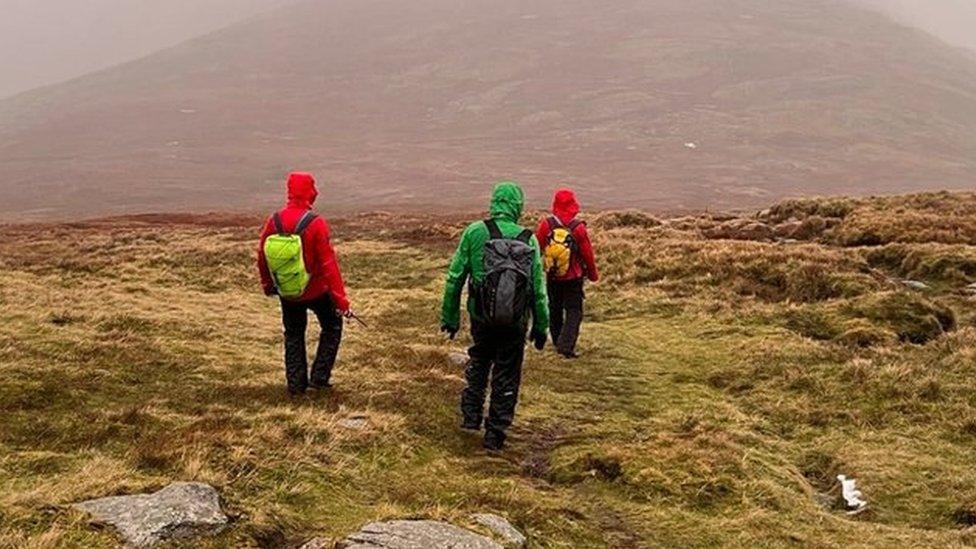 Three volunteers walking on fell in mist