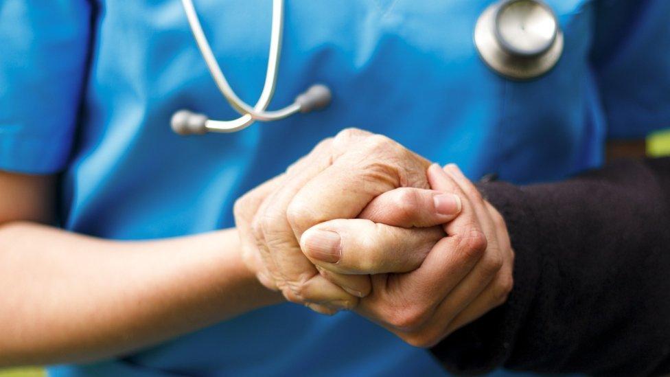 A doctor holds a patients' hand