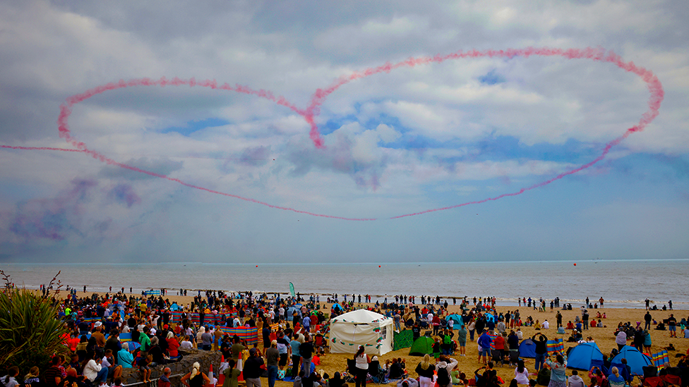 Pink heart in the sky about a crowd on a beach in Swansea