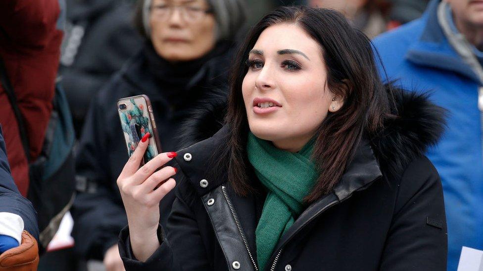 Laura Loomer holding a phone across the the New York Women's March 2019