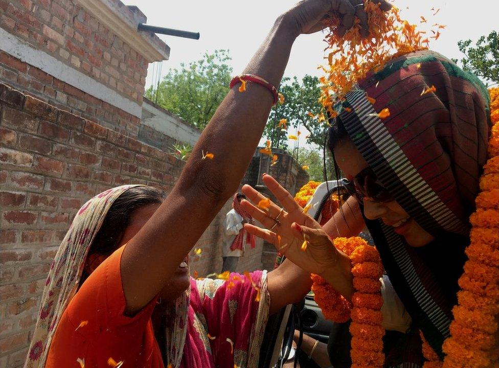 A supporter throws marigold petals at Mahua Moitra