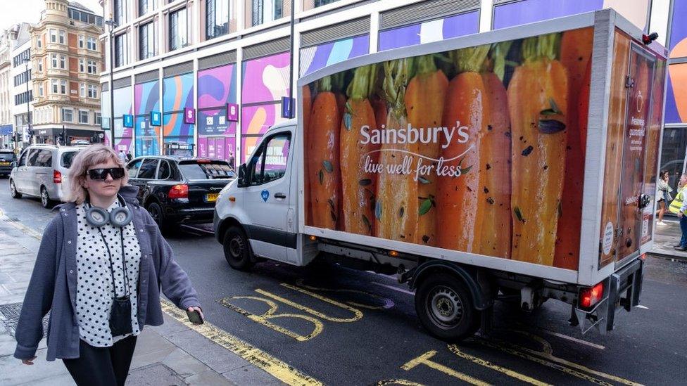 A woman walks past a Sainsbury's van