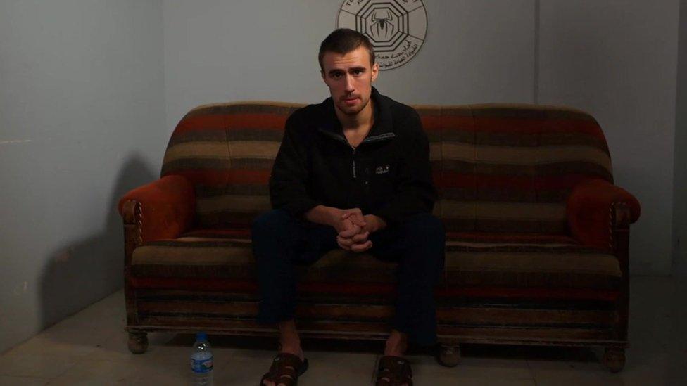 Jack Letts, aka Jihadi Jack, sitting on a striped sofa in a Kurdish jail in northern Syria