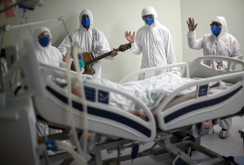 Health workers from the Portuguese charity hospital in Belem, Para State, Brazil, sing and pray for a COVID-19 patient inside the hospital wards and ICU areas as part of Easter celebrations, 4 April 2021