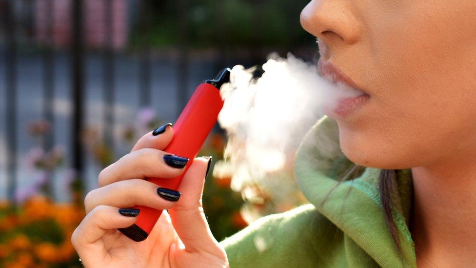 A stock photo of a woman vaping