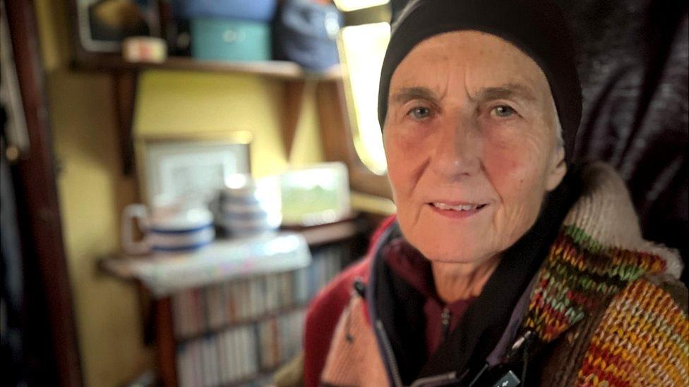 Continuous cruiser Pamela Smith wearing a black headband sat in her canal boat