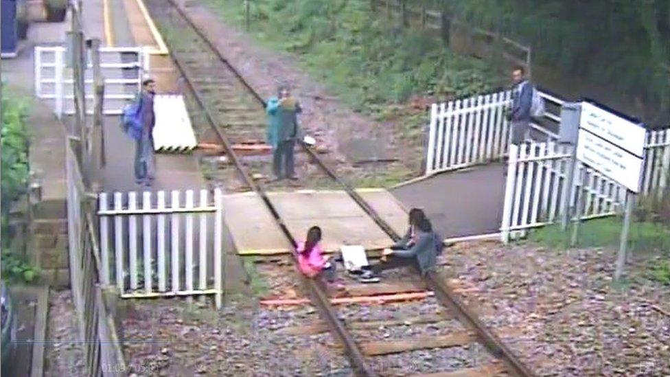 Children sit on rails while woman takes photos