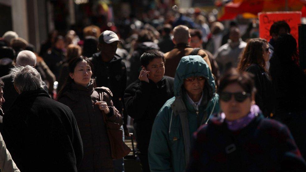 Pedestrians walk down a city street in New York City on 25 March 2011