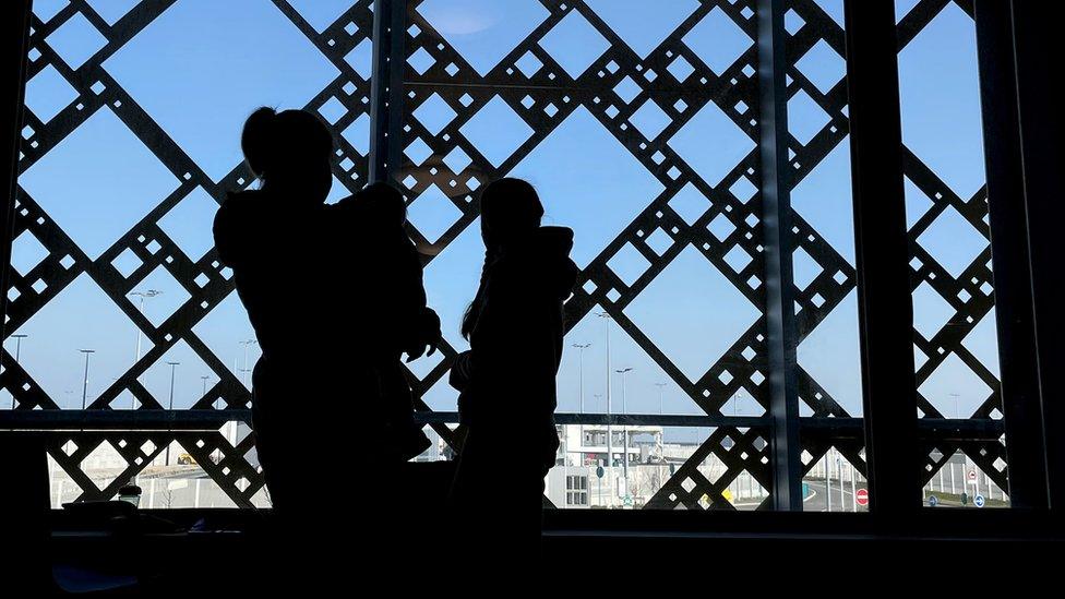 Members of a Ukrainian family wait for paperwork to be completed at the ferry terminal in Calais, France