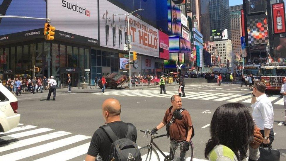 A red car is wedged against a lamp post after crashing in New York's Times Square