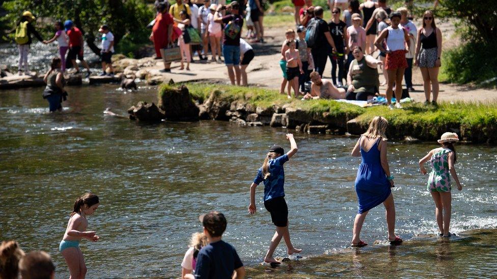 People walk across the River Dove in Dovedale in the Peak District