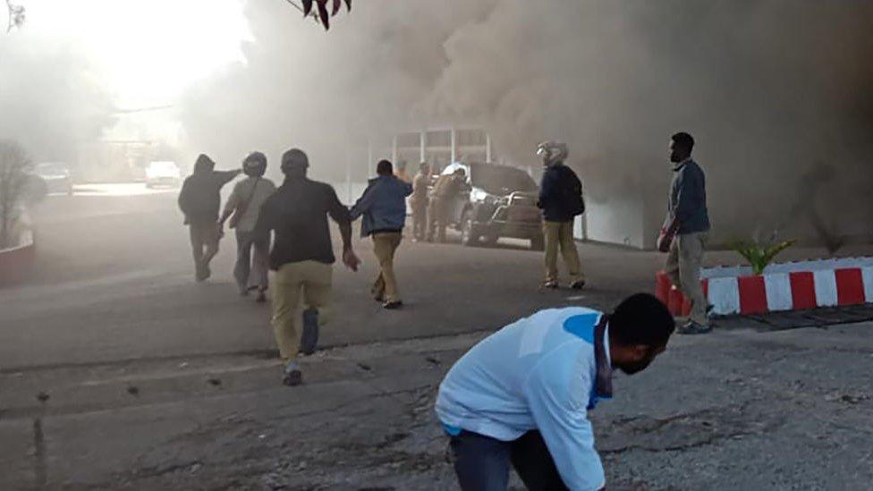 People react as a building burns after fresh protests broke out in Wamena on September 23, 2019