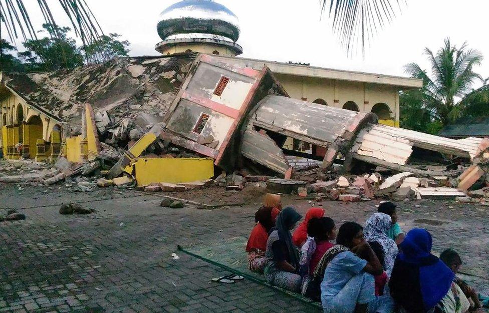 Residents gather outside a damaged mosque, its minaret reduced to rubble following its collapse, after a 6.5-magnitude earthquake struck the town of Pidie, Indonesia's Aceh province in northern Sumatra, on 7 December 2016