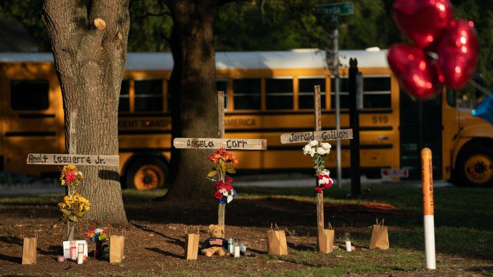 Morning sun shines on memorials for Jerrald Gallion, Angela Carr and AJ Laguerre Jr near a Dollar General store where they were shot and killed on Saturday