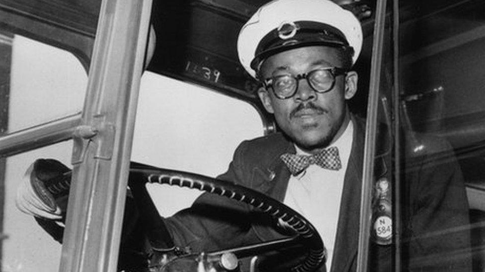 A Black London bus driver at the wheel in the late 1950s