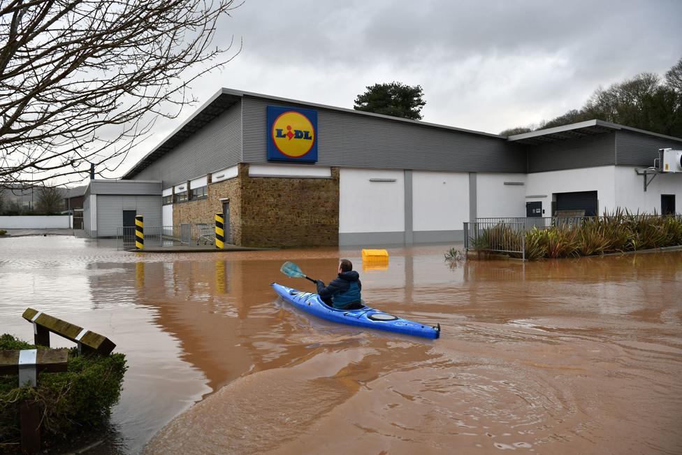 A canoeist makes their way past a flooded supermarket in Monmouth.