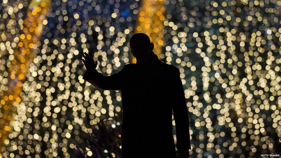 Barack Obama in front of a Christmas tree with lights