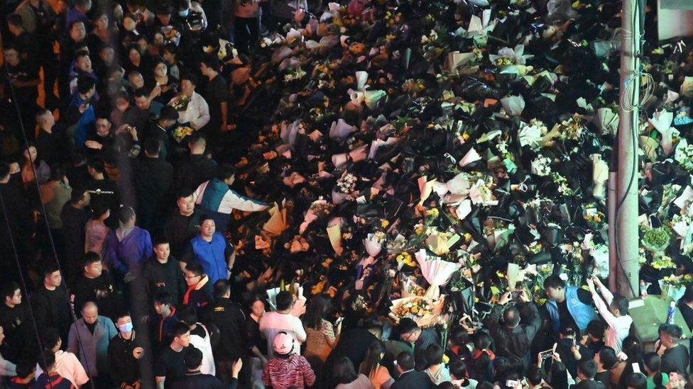 People mourn and lay bouquets outside Li's childhood home in Hefei