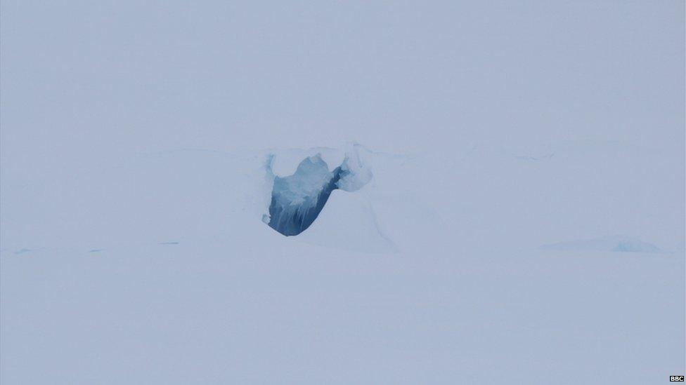 A pure white scene with a noticeable crevasse, which is blue inside