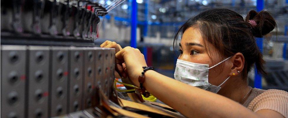 An employee checking on a circular weaving machine at a textile factory in Shangqiu