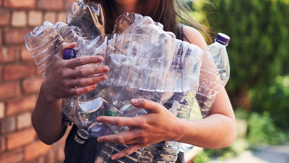 Person holding lots of empty plastic bottles