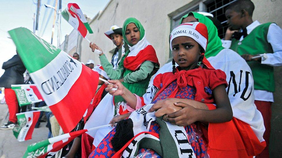 People wave flags as soldiers and other military personnel of Somalia's breakaway territory of Somaliland march past during an Independence day celebration parade in the capital, Hargeisa on May 18, 2016