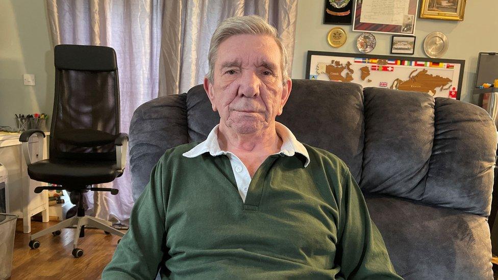 John V. Heath sitting in a chair wearing a green polo shirt