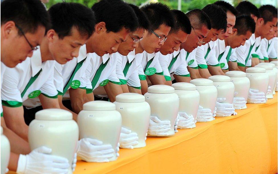 Attendants place biodegradable urns on a table at a cemetery in Tianjin, northern China, for a collective eco-burial on 20 July 2010.