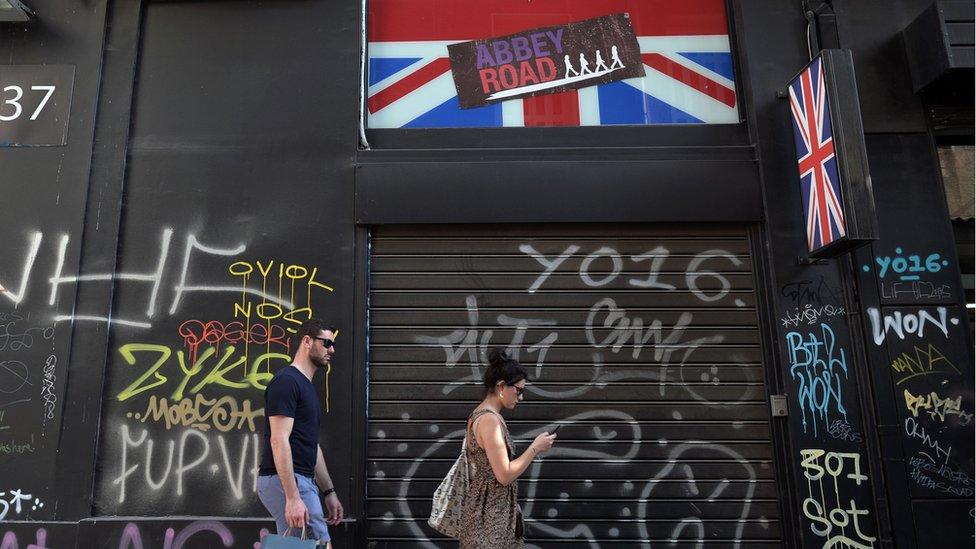 A picture of a man and woman waling past a shop front with a union jack sign above it